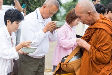 İnsanlar gıda teklifleri yapmak için bir Budist keşiş 's sadaka kase koyun.