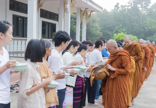 As pessoas colocam ofertas de comida na tigela de esmolas de um monge budista para fazer — Fotografia de Stock