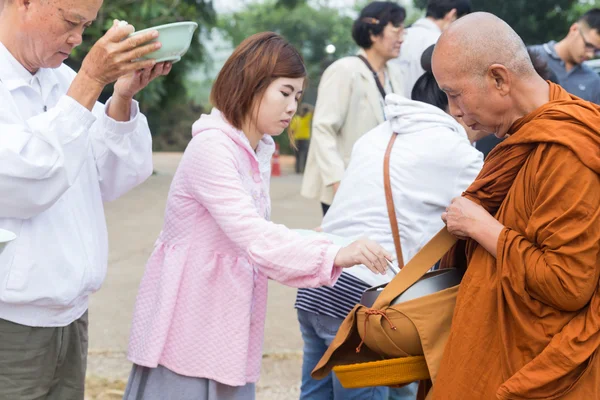 La gente pone ofrendas de comida en un tazón de limosna budista para hacer — Foto de Stock