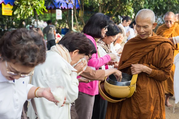 La gente pone ofrendas de comida en un tazón de limosna budista para vir —  Fotos de Stock