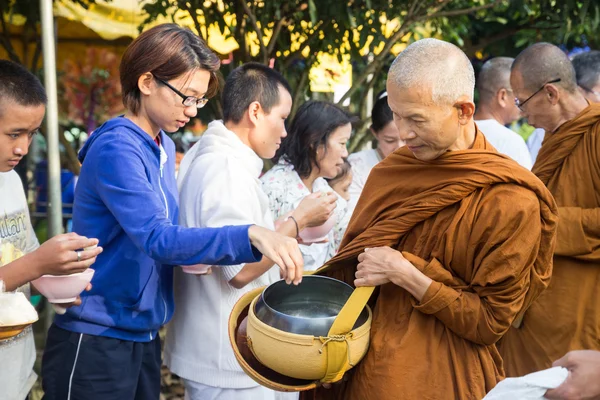 Lidé dát nabídky potravin v buddhistický mnich almužny mísa pro vir — Stock fotografie