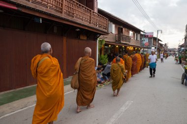 İnsanlar koymak gıda teklifleri bir alm içinde bildirmek için yürüyen Budist rahip