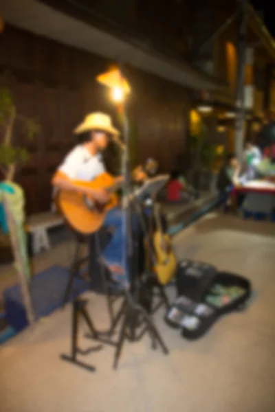 L'image floue d'un musicien de rue asiatique arrachant une guitare — Photo
