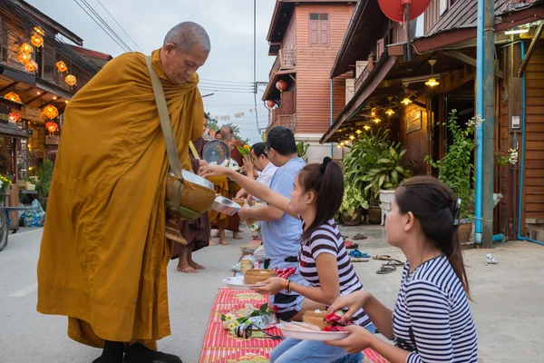 As pessoas colocam ofertas de comida na tigela de esmolas de um monge budista para gosma — Fotografia de Stock