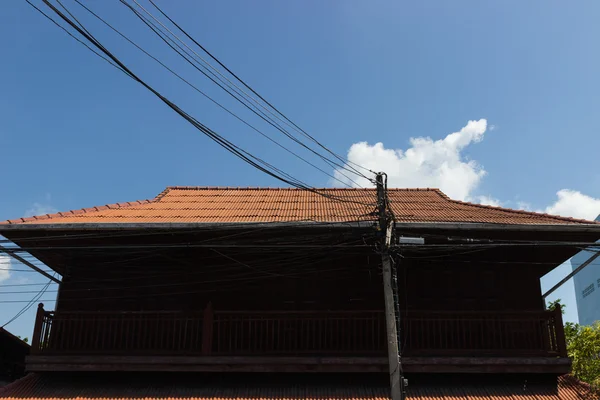 Poteau électrique devant la maison en bois — Photo