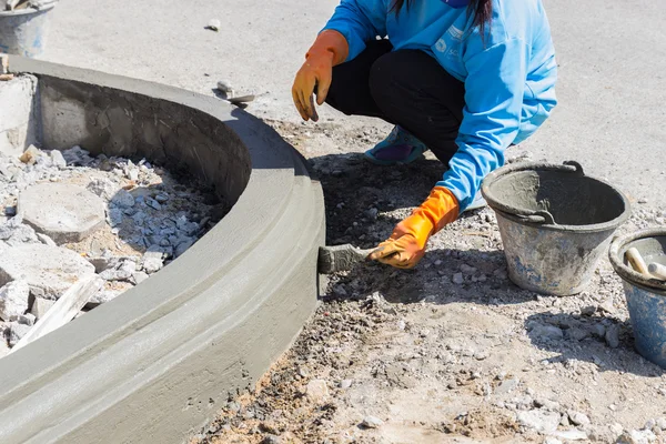 Рабочий наносит цемент на поверхность края тропинки — стоковое фото