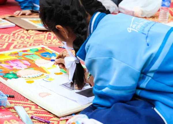 The asian girl is painting crayon color on her drawing for draw — Stock Photo, Image