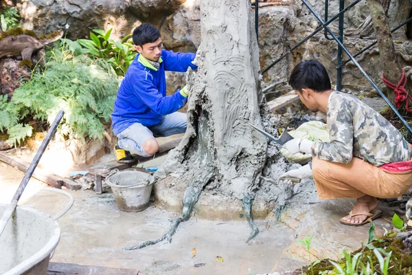 Workers are grout cement on the fake tree trunk — Stock Photo, Image