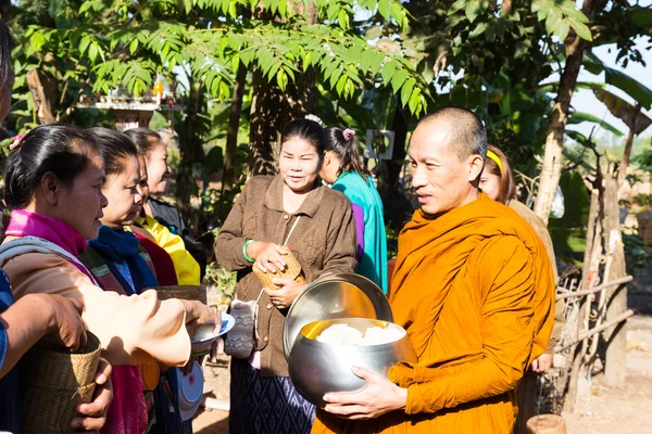 Mensen brengen voedsel op boeddhistische monnik alms bowl — Stockfoto