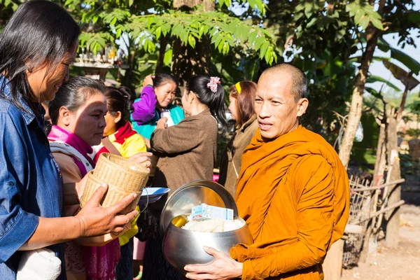 Mensen brengen voedsel op boeddhistische monnik alms bowl — Stockfoto