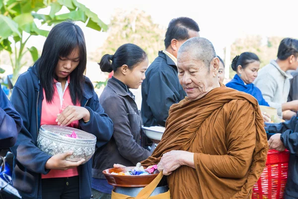 Människor sätter mat på buddhistisk munk alms skål — Stockfoto