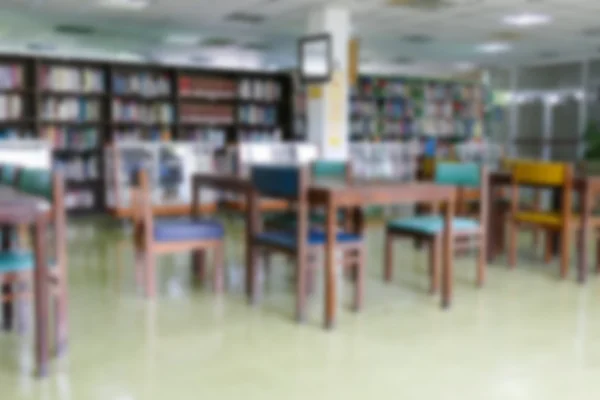 Blurry defocused image of book shelf, wooden desk and chair for — Stock Photo, Image