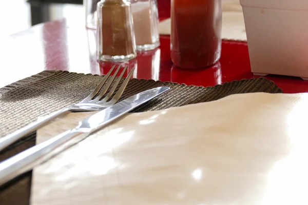 Gaffel, kniv, honung, peppar och salt på rött bord — Stockfoto
