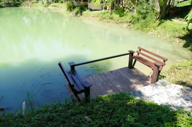 İskele ve balık gölet üzerinde ahşap koltuk