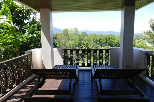 Деревянный шезлонг на балконе с видом на лес и небо — стоковое фото
