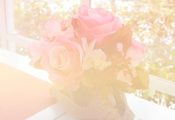 Rosa rosa falsa sobre mesa blanca cerca de la ventana con vista al jardín (colo —  Fotos de Stock
