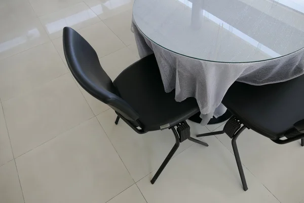 Chaise en cuir noir et table ronde avec nappe grise — Photo