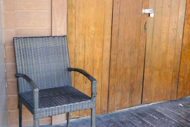 siyah hasır sandalye ahşap duvar yanında 