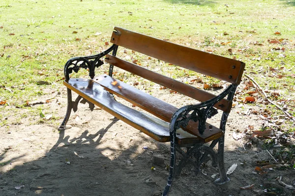 Houten bankje in de schaduw van grote boom — Stockfoto