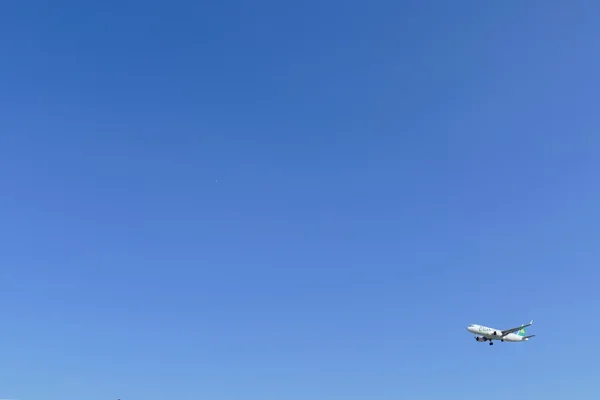 The airplane is flying in blue sky — Stock Photo, Image