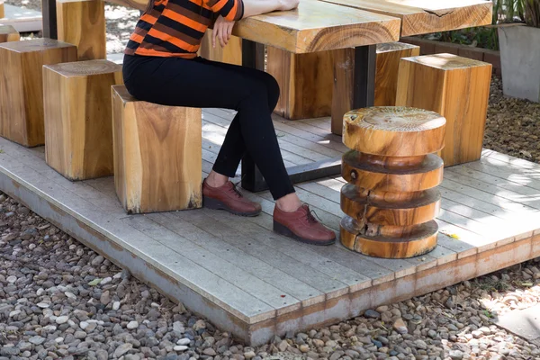 Niña con pantalones negros y zapatos de cuero marrón sentado en madera — Foto de Stock