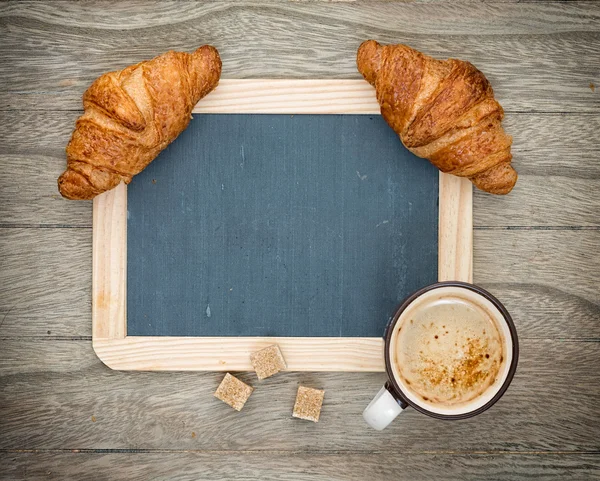 Kaffee und Croissant auf einem Holzbrett — Stockfoto