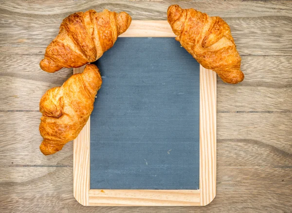 Croissants frescos assados na mesa de madeira — Fotografia de Stock