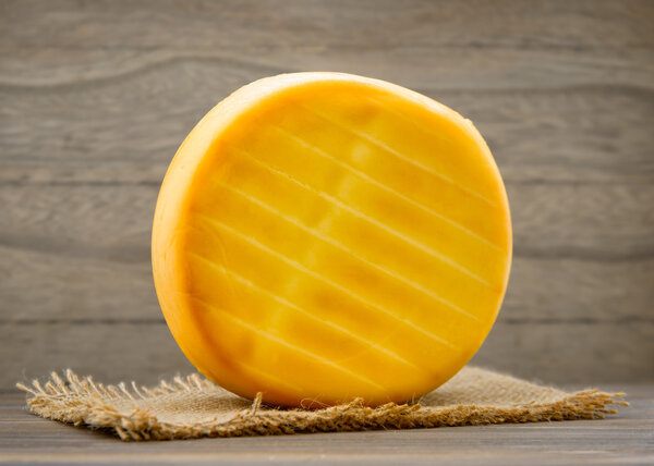 Smoked cheese wheel on wooden table