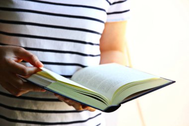 Kadın açık bir kitap tutuyor, ev hanımı evde boş vaktini rahatlamak için roman okuyarak geçiriyor.