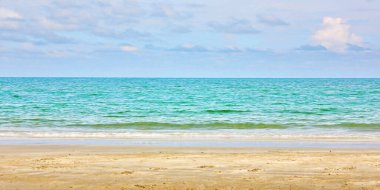 Mavi gökyüzü beyaz bulut panarama arkaplanlı güzel deniz kumsalı.