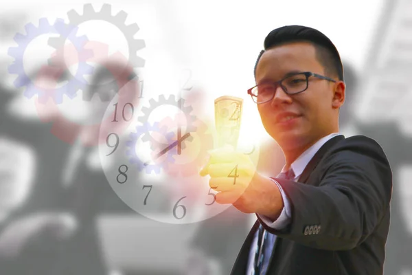 business man catching dollar bank note in hand with illustration of clock and gears on blur workers background , money earning concept