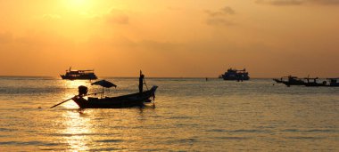 Güneşin doğuşuyla çalışan balıkçıyla gölgeli uzun kuyruk teknesi soyut doğa arka planı.