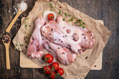 Yarı bitmiş kümes hayvanları. Saf hindi kanadı. Etrafı sebze, baharat ve otlarla çevrili. Koyu ahşap bir arka planda. Kümes hayvanları kızarmaya hazır.