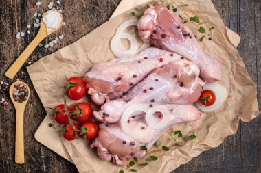 Yarı bitmiş kümes hayvanları. Saf hindi kanadı. Etrafı sebze, baharat ve otlarla çevrili. Koyu ahşap bir arka planda. Kümes hayvanları kızarmaya hazır.