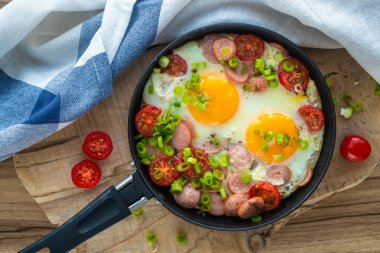 Sosisli, domatesli ve sebzeli omlet. Geleneksel kahvaltı yemeği. Ahşap arkaplanda düz bir görünüm yatıyordu