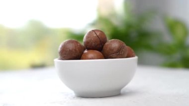 Bir kasedeki Macadamia fındıkları masada dönüyor. Kamera hareket ediyor. Parallaks etkisi. Yakın çekim görüntüleri.