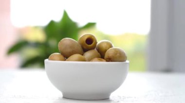 Bir kasede yeşil tuzlu zeytin masada dönüyor. Kamera hareket ediyor. Parallaks etkisi. Yakın çekim görüntüleri.