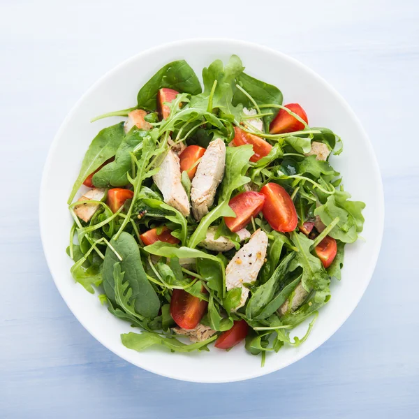 Fresh salad with chicken, tomato and greens (spinach, arugula)