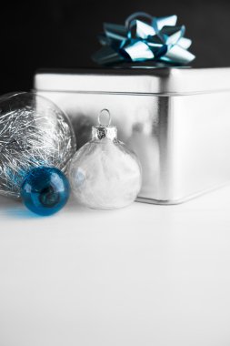 Beyaz ve siyah ahşap arka planlar üzerinde mavi yay ve xmas baubles ile Metal hediye kutusu. Mutlu noel kartı. Kış tatilleri. Xmas teması. Yeni Yılınız Kutlu Olsun.