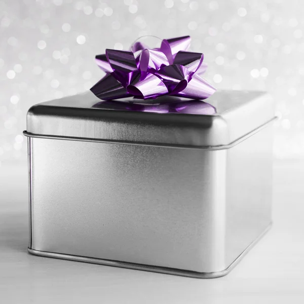 Metal gift box with purple bow on white glitter background. Merry christmas card. Winter holidays. Xmas theme. Happy New Year.