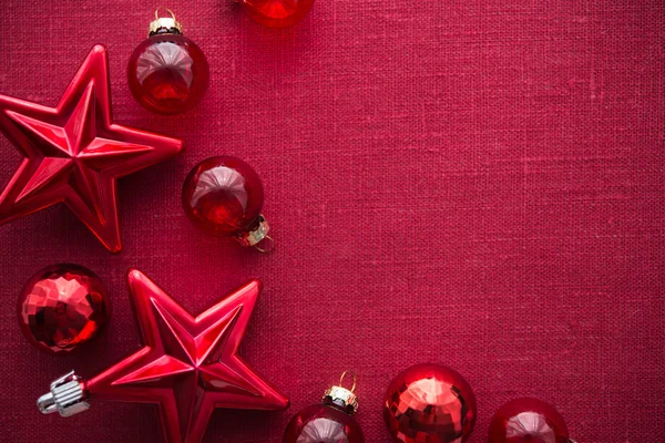 Red christmas decorations (stars and balls) on red canvas background. Merry christmas card. Winter holidays. Xmas theme. Happy New Year. — Stock Photo, Image