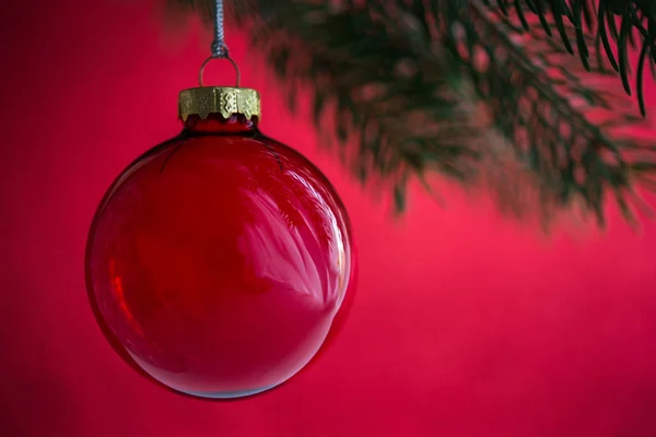 Bola roja de Navidad en el árbol de Navidad sobre fondo rojo bokeh. Feliz tarjeta de Navidad. Vacaciones de invierno. Tema de Navidad. Feliz Año Nuevo . —  Fotos de Stock