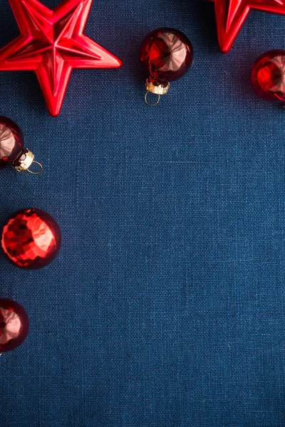 Red christmas decorations (stars and balls) on dark blue canvas background. Merry christmas card. Winter holidays. Xmas theme. Happy New Year.