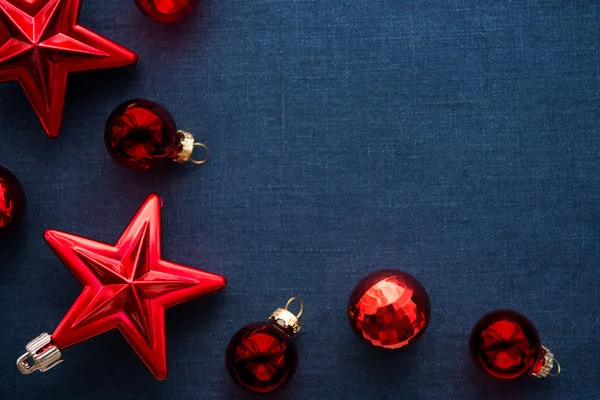 Decoraciones rojas de Navidad (estrellas y bolas) sobre fondo de lona azul oscuro. Feliz tarjeta de Navidad. Vacaciones de invierno. Tema de Navidad. Feliz Año Nuevo . —  Fotos de Stock