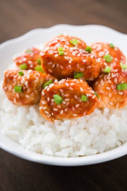 Susam ve koyu ahşap zemin üzerine pirinç ile baharatlı tatlı ve ekşi tavuk kapatın. Oryantal gıda.