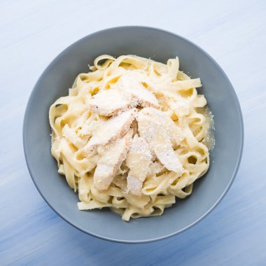 Mavi ahşap arka plan üst görünümünde tavuk ve parmesan ile Makarna fettuccine alfredo. İtalyan mutfağı.