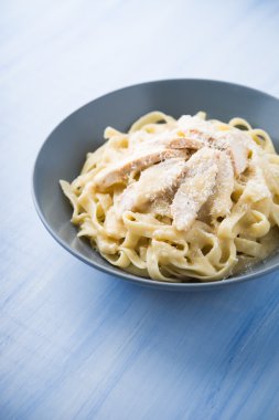 Pasta fettuccine alfredo tavuk ve parmesan mavi ahşap arka plan yakın. İtalyan mutfağı.