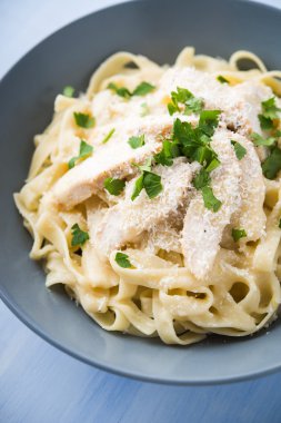 Makarna fettuccine alfredo tavuk ile, parmesan ve maydanoz mavi ahşap arka plan üzerinde yakın. İtalyan mutfağı.