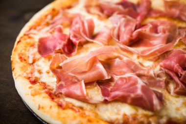 Pizza prosciutto ile (parma jambon) koyu ahşap arka plan üzerinde yakın. İtalyan mutfağı.