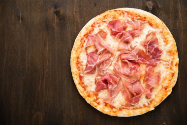 Koyu ahşap arka plan üst görünümünde prosciutto (parma jambon) ile Pizza. İtalyan mutfağı. 